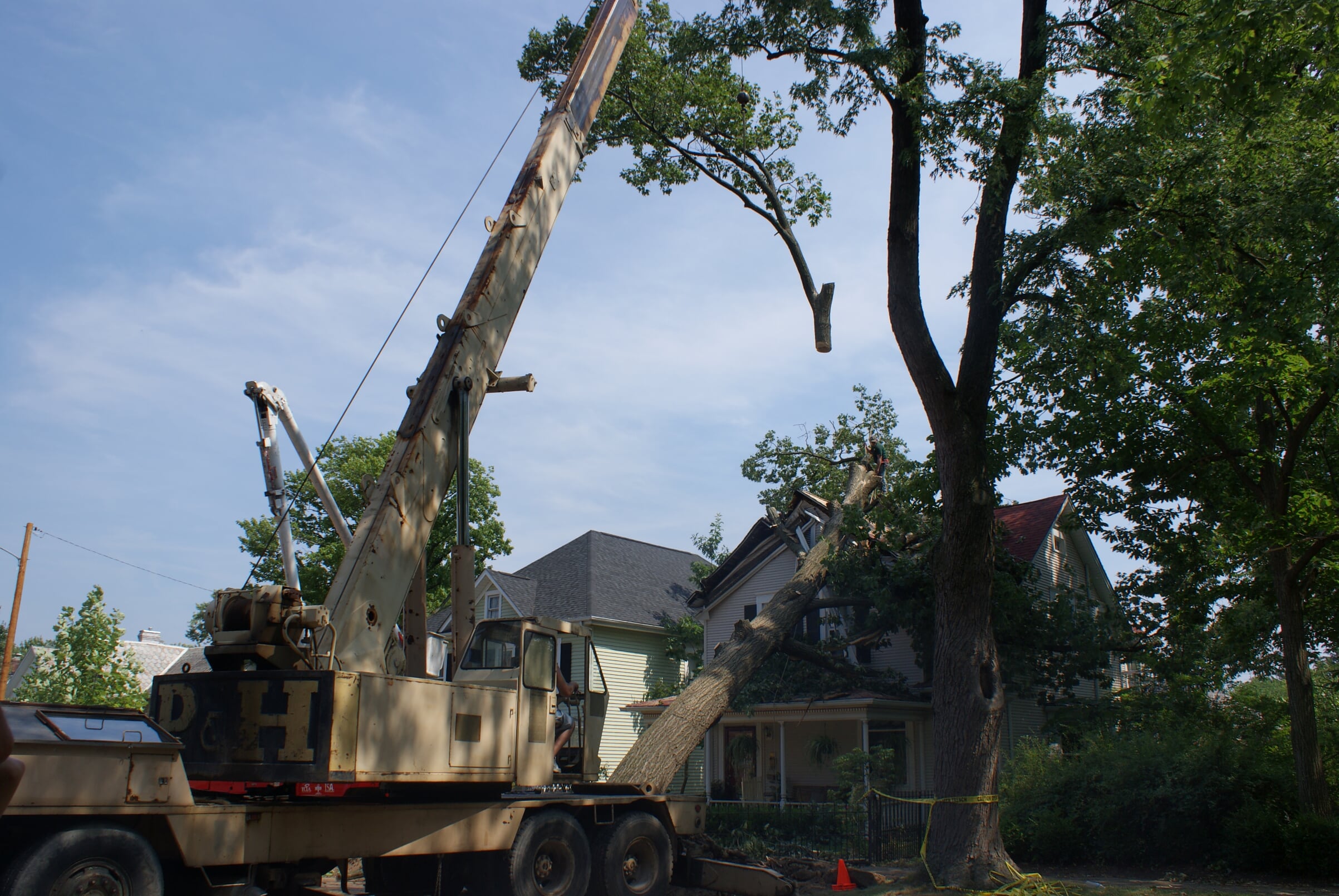 Mid Ohio Tree Service crane lifting a large log section over a house
