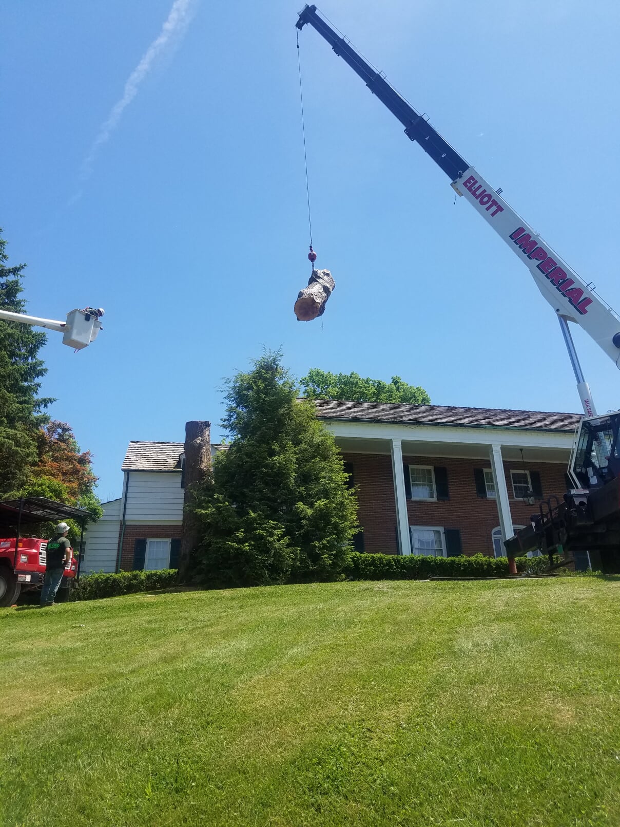 Mid Ohio Tree Service crane lifting a large log over a brick home